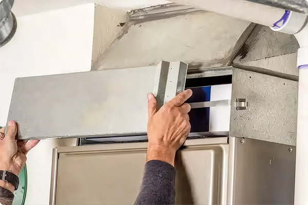 Technician removing the access panel from a furnace to reach the filter and blower compartment