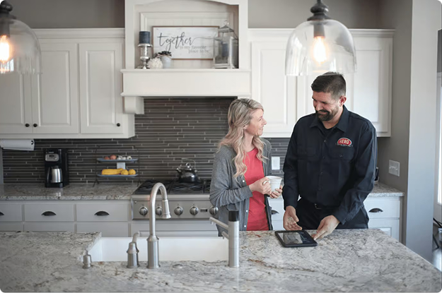 Hero technician showing information on a tablet to a homeowner at a kitchen island