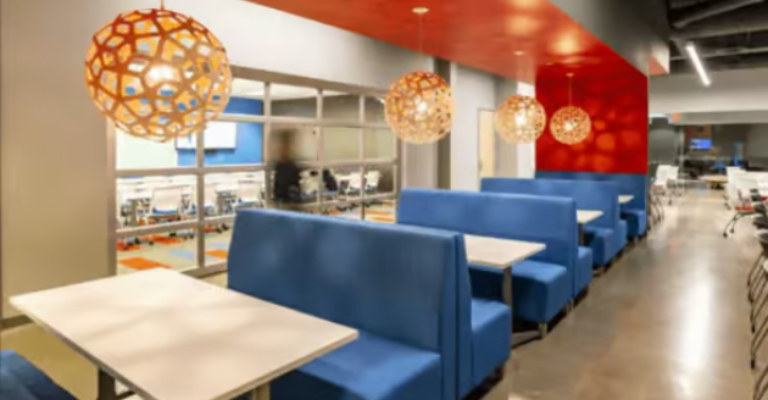 Open office break area with blue booth seating, wood tables and woven pendant lights