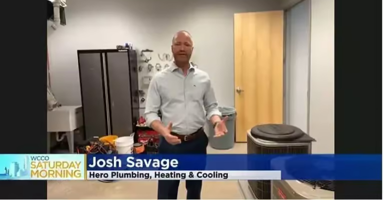 Josh Savage of Hero Plumbing, Heating & Cooling being interviewed in a utility room during a WCCO Saturday Morning segment